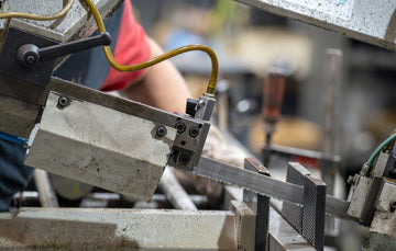 Professional using a band saw with blade guard lowered, clear guideline light, proper PPE, cutting a wood board in a clean workshop